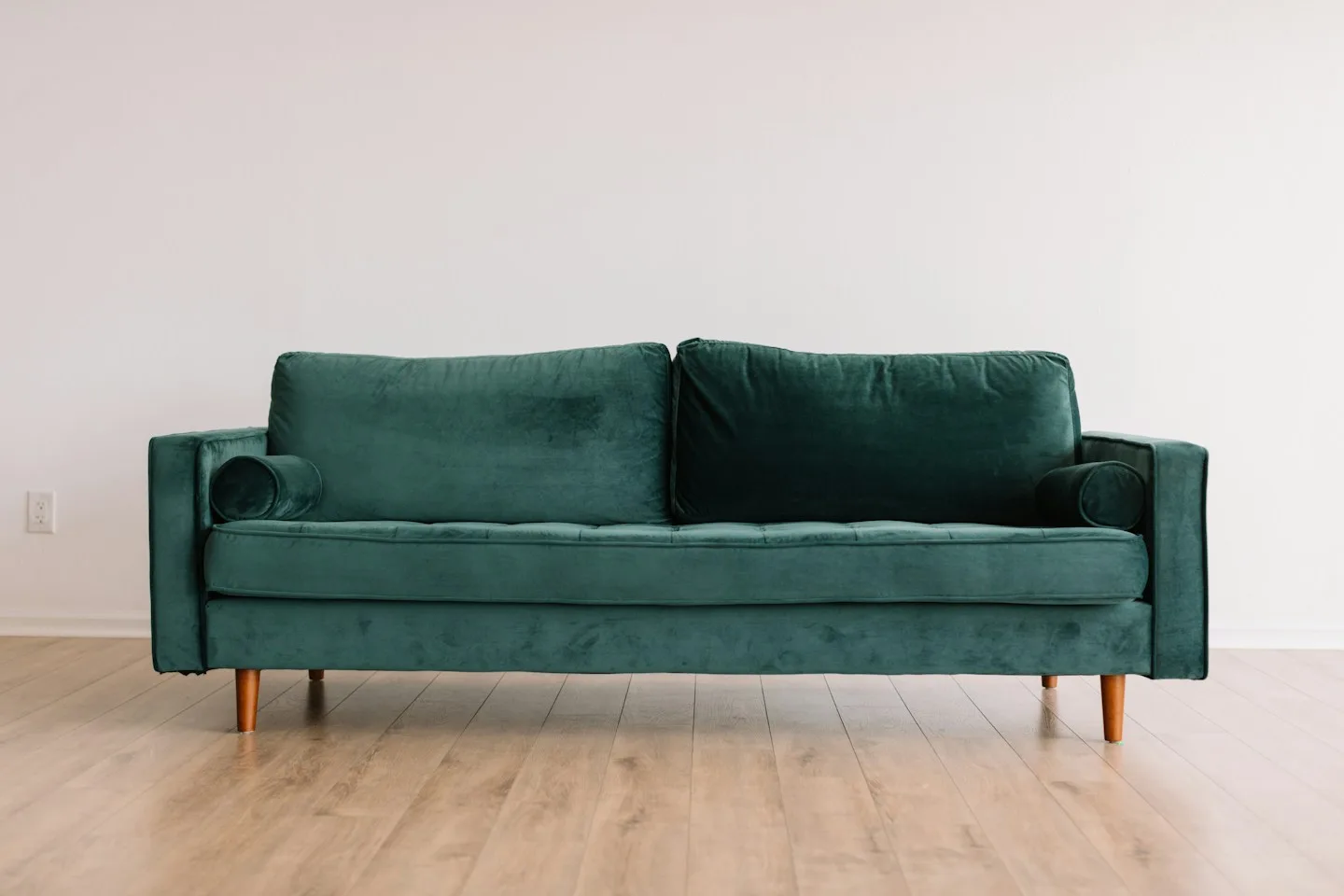 A green velvet sofa in an empty room